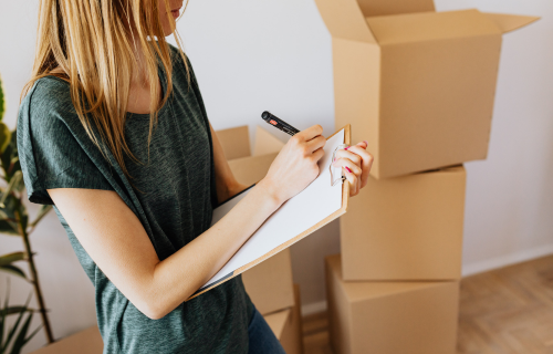 A woman with a clipboard next to a pile of boxes