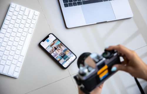 Person taking a photo with a camera of a desk with keyboard, laptop and mobile